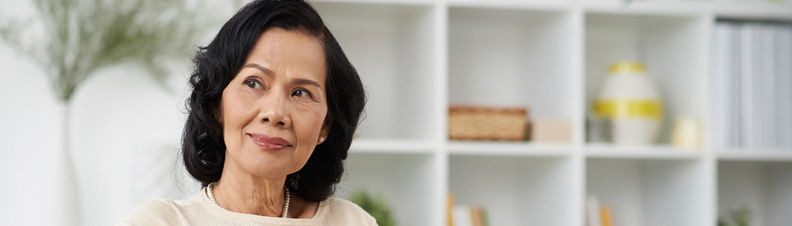 Retirement aged woman of Asian descent looking thoughtfully into the distance